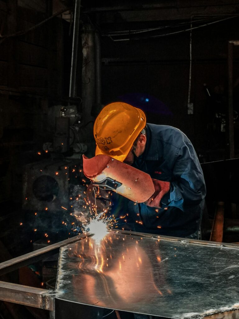 pexels photo 2480481 2480481 A welder wearing protective gear works on metal in an industrial workshop, surrounded by sparks.